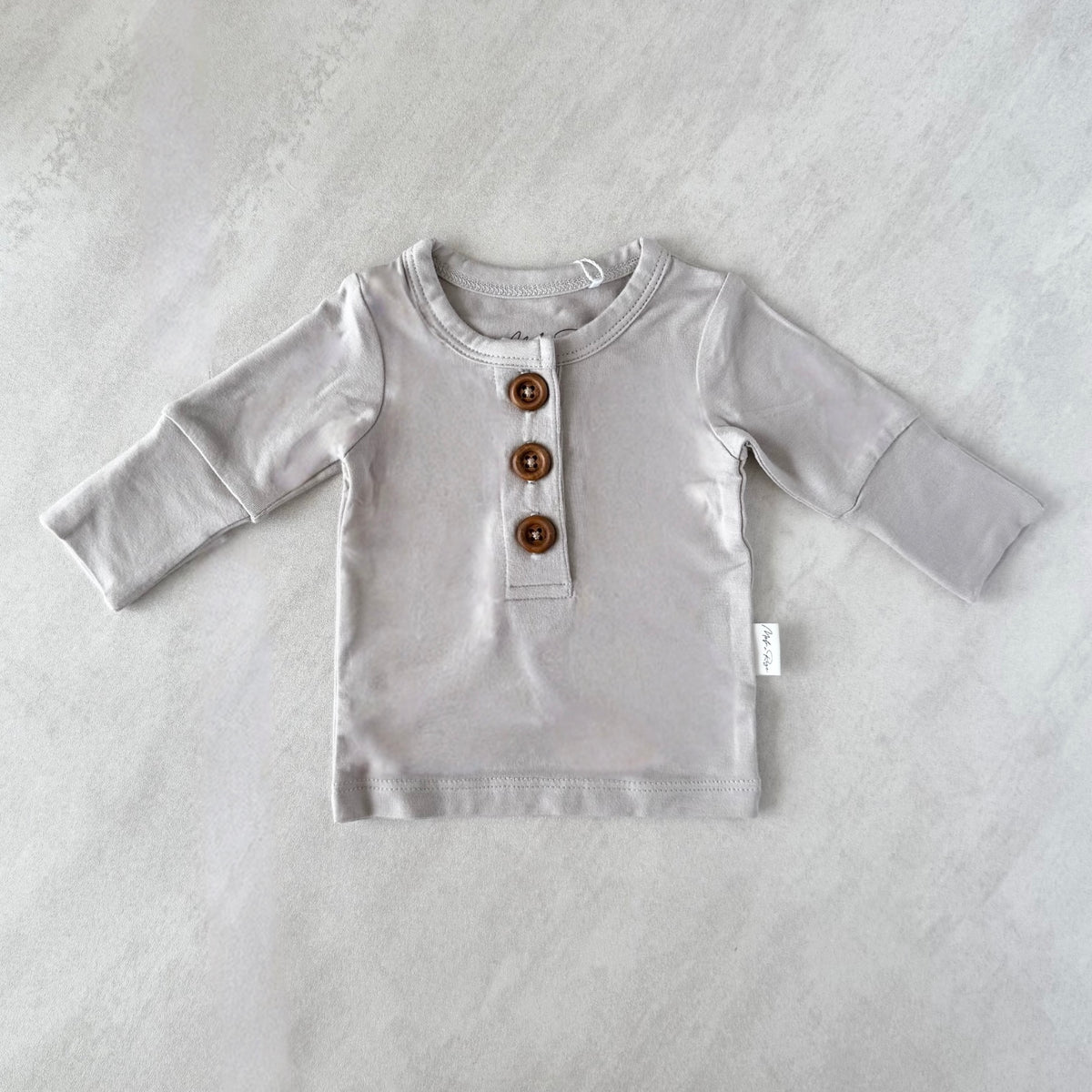 Gray long-sleeve shirt with brown buttons for preemie baby on a light gray background