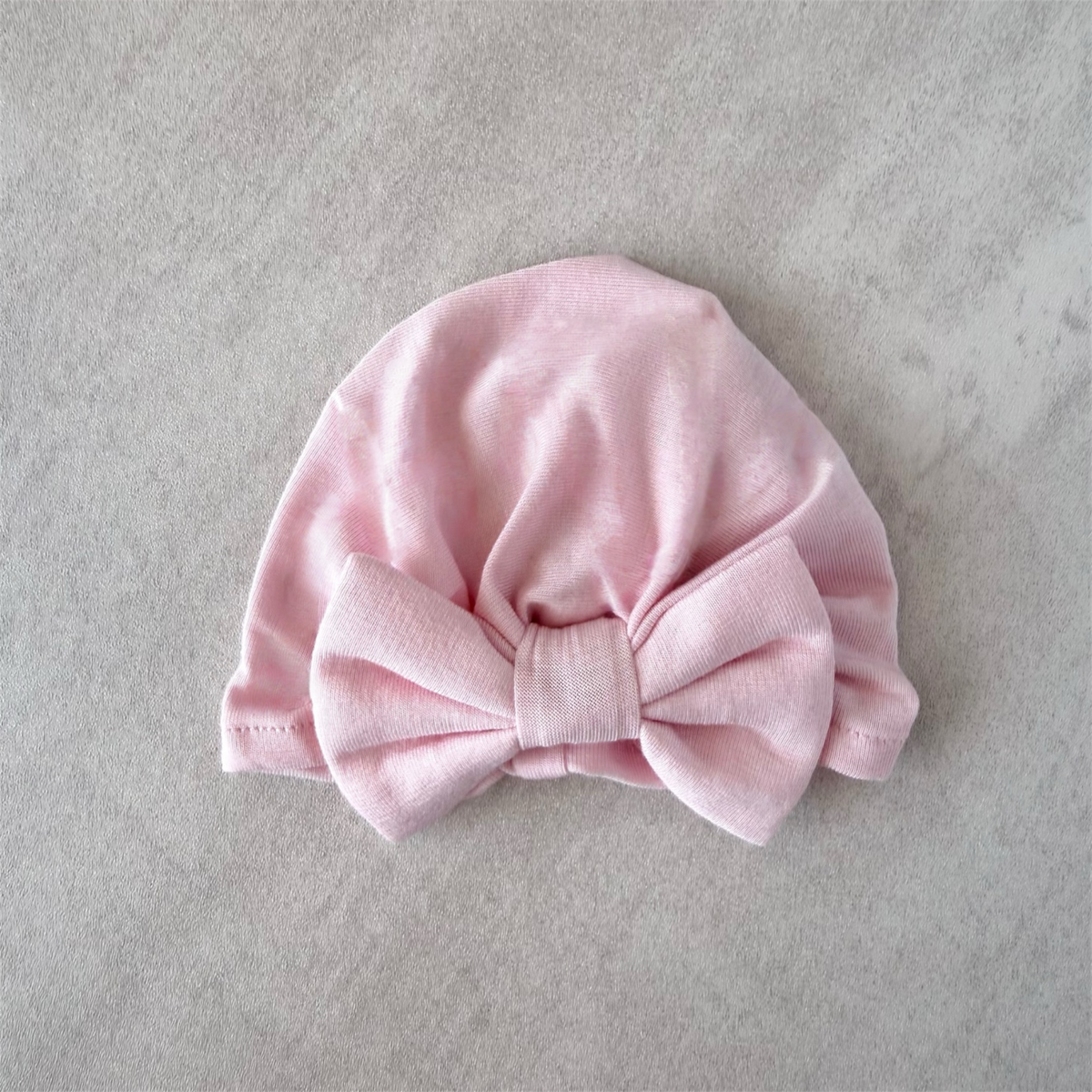 Pink premature preemie baby turban with a bow on a gray background