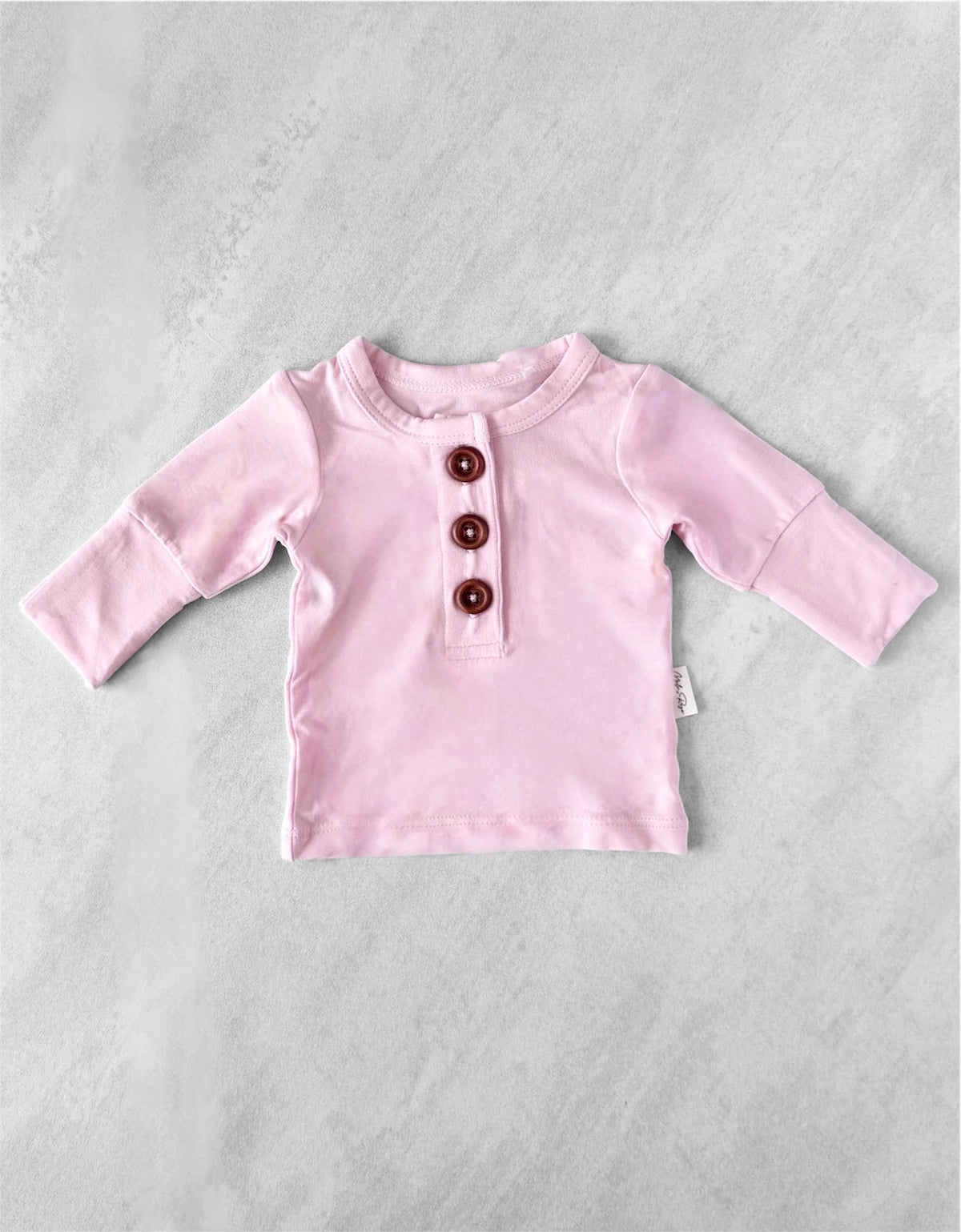 Pink premature baby shirt with buttons on a light gray background