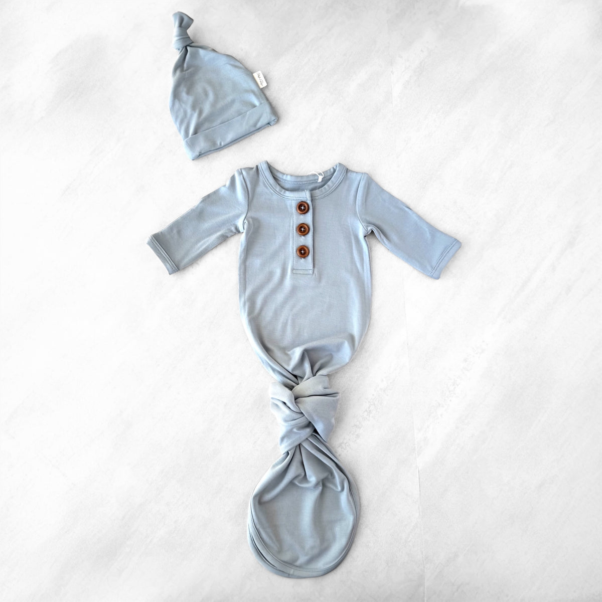 Light blue premature baby outfit with long-sleeve shirt and knotted wrap on a white background