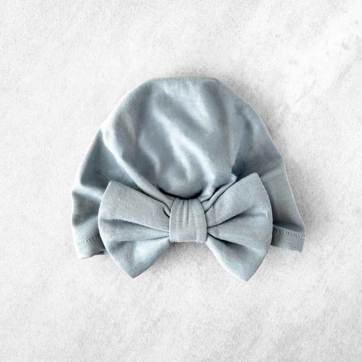 Light blue preemie baby turban with a bow on a light gray background